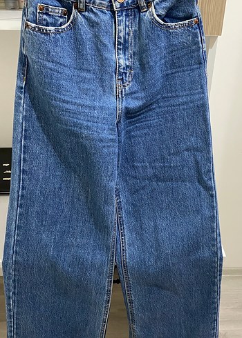Kadın koyu mavi, yüksek bel, geniş paça jean.