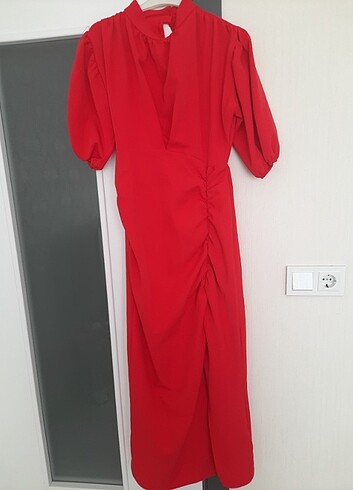 Kırmızı büzgülü yırtmaç detaylı, balon kollu abiye elbise.