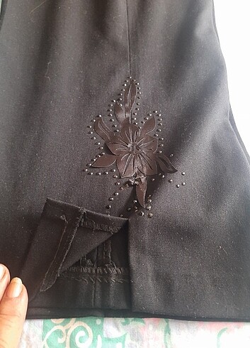 Siyah paçası çiçek taş detaylı pantolon.